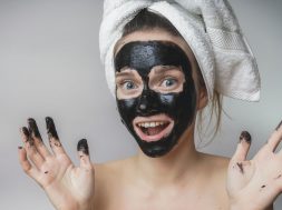 Happy joyful woman applying black mask on face.Skin care,clean p